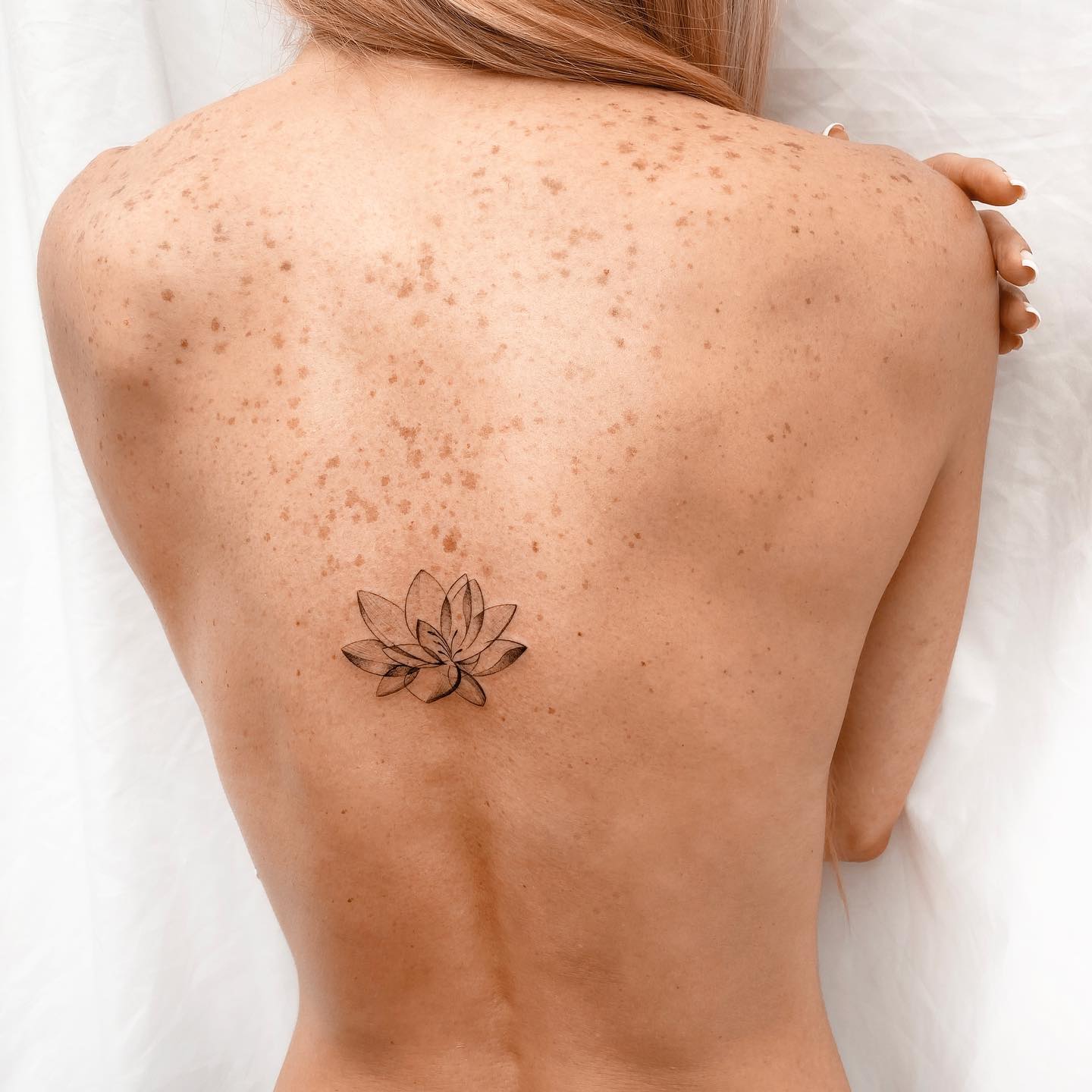 One line rose tattoo on the upper back.