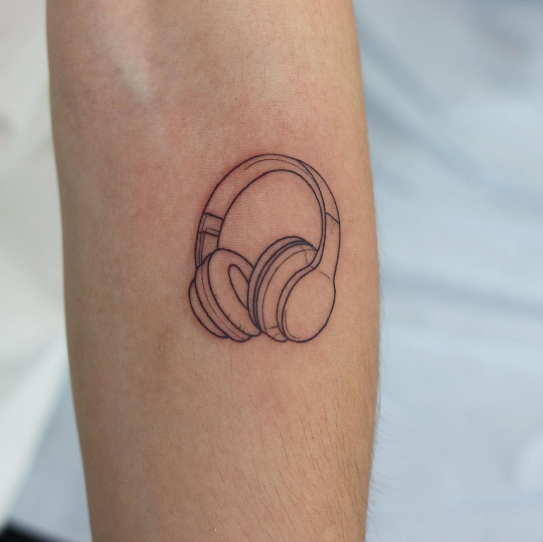 Girl with over the ear headphones walking down a dark road at night.  Looking from behind tattoo idea | TattoosAI