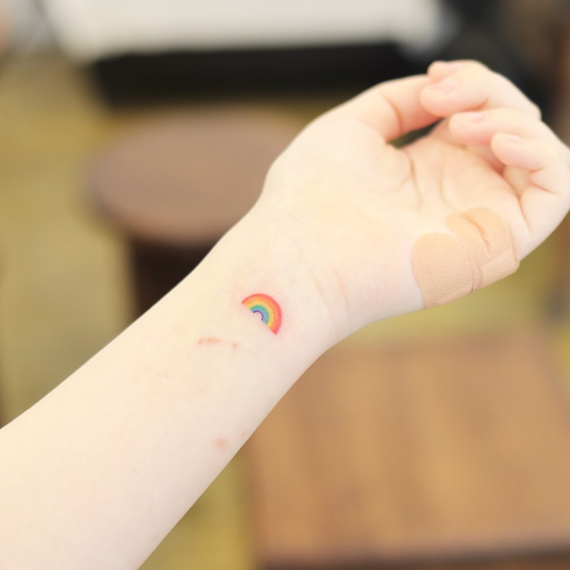 Small rainbow tattoo on the left tricep