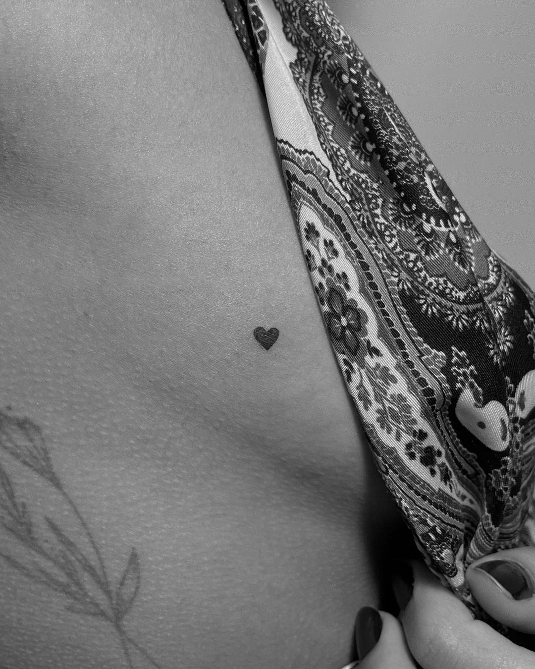 Minimalist red heart tattoo on the breast.