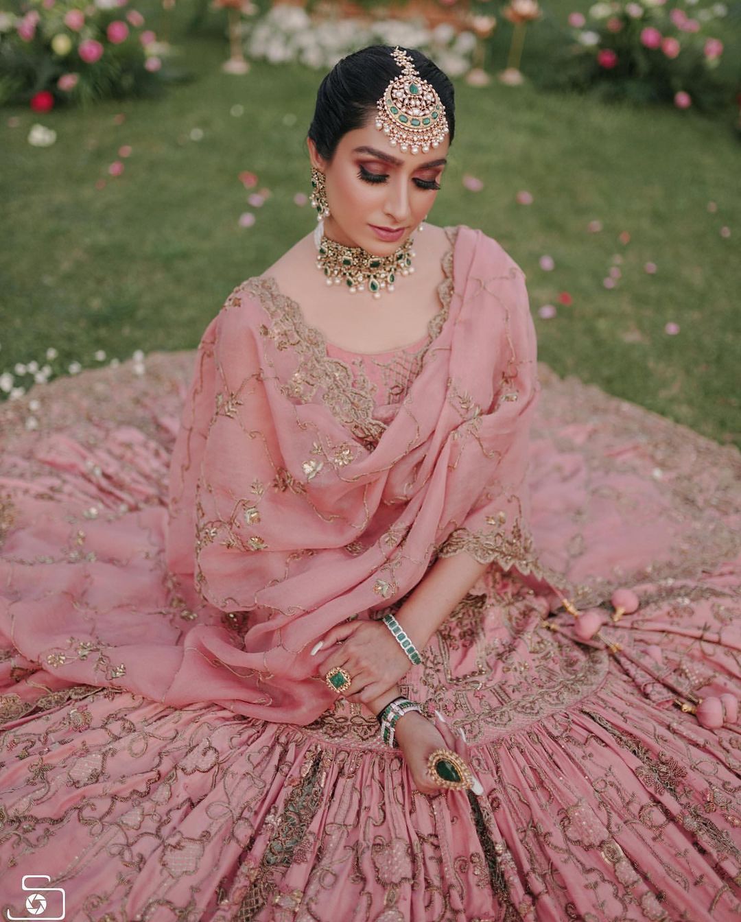 Photo of kiara advani wearing light pink lehenga and contrasting emerald  jewellery on her wedding day